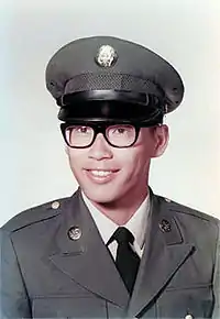 Asian American male wearing Army Dress Green Uniform and glasses posing for a photo.