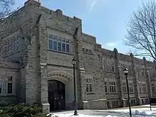 Three-storey building constructed with a sandstone exterior, and an archway over the front entrance