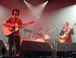 Several men performing onstage playing and singing into a microphone