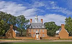 A three-story red brick colonial-style hall and its left and right wings during summer.