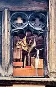 close up of the single window on the first floor, which has quatrefoils carved into the old oak wood