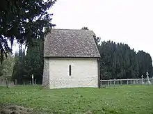 A small structure with a white painted wall and a tiled roof