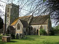 Stone building with square tower, partially obscured by trees.