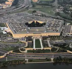 Aerial view of the huge five-sided building and its multiple rings. Parking lots and highways stretch away from it.