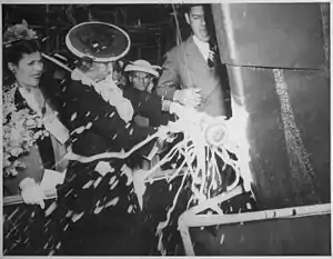 Woman smashing a bottle on the bow of a ship