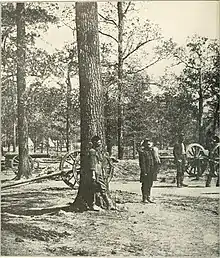 Black and white photo shows Civil War soldiers with artillery limbers and heavy cannon at left.