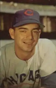 A man wearing a blue baseball cap with a red "C" on the front and a white baseball jersey with "Chicago" written across the chest in blue