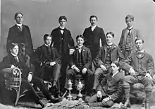 Black and white team photo with the Cosby Cup in the foreground