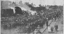 Black and white photo show a wreck surrounded by onlookers