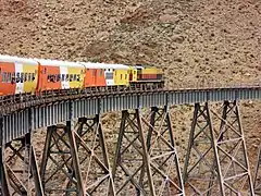 Orange, yellow and white train crossing a ravine