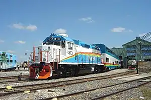 A pair of DMUs trailing behind EMD GP49 engine 813 in Hialeah Railyard