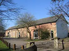 A long stone building with windows, doors, filled openings and round pitch holes