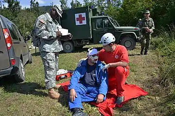 U.S. Army Sgt. 1st Class Ahmad Whitted, standing, an observer-controller, monitors the interaction between a role player and a Slovenian Civilian Protection agent Aug. 25, 2014, in Postojna, Slovenia