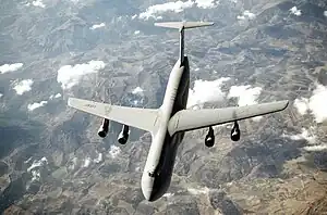 Top view of four-engine jet transport in flight above mountain range