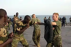 US Navy 051103-M-2175L-200 U.S. Marine Corps Lance Cpl. Ryan Papa, right, assigned to 2nd Platoon, Company C, 1st Battalion, 8th Marine Regiment, holds a striking pad for a member of the Senegalese 90th Naval Infantry.