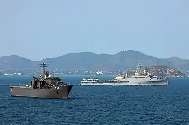 RSS Resolution at anchor in the Gulf of Thailand, with USS Denver passing behind during Cobra Gold '11.