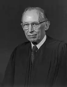 monochrome photographic portrait of a white man in late middle age in judicial robes.  He wears glasses and has thinning hair.