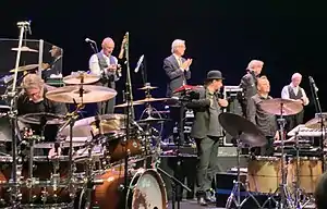 King Crimson at the Sapporo Culture Arts Theatre in Japan, on 2 December 2018. From left to right: Pat Mastelotto, Tony Levin, Bill Rieflin, Jeremy Stacey, Jakko Jakszyk, Gavin Harrison and Robert Fripp (Mel Collins not shown)