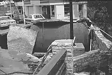 An underground storage tank about the size of a small car has come up out of the ground breaking the pavement that used to cover it.