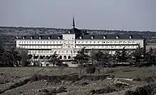 Picture of beige 4 story building with blue sky and green grass.