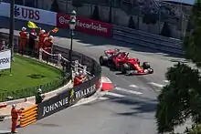 Sebastian Vettel in a scarlet red Formula One car with his right hand out of the cockit to celebrate a race win