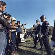 A protester hands a trooper a flower.