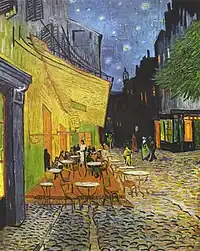 The outdoor terrace of a cafe with several tables filled with patrons. People are walking along the street under a starry sky.