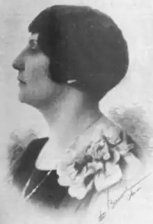 A white woman with short dark hair, in profile, wearing a corsage