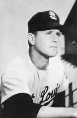 A man in a light baseball uniform and dark cap