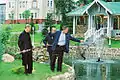 George Bush and Vladimir Putin fish from a fish pond, while an aide holds a landing net