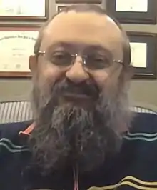 Zelenko in a striped shirt with certificates in background