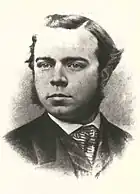 A young man with sideburns wearing a suit