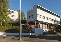 A modernist building with columns in one floor and a row of windows one floor higher