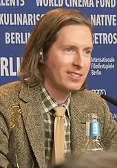 A bob-haired man sitting at a movie conference