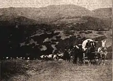 sepia picture of pioneers crossing the plains of the midwestern united states with horses and covered wagons; a still from the 1913 film one hundred years of mormonism