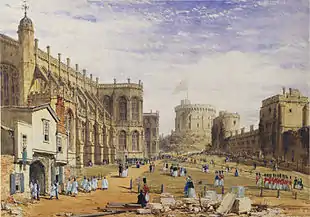 A painting showing a stone chapel on the left, with a timber built entrance, out of which are parading a number of white clad individuals. In the middle of the painting is a grassy area, across which are marching various red-uniformed soldiers. On the right hand side is a line of stone buildings, with a circular tower on a mound in the far distance.