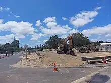 An excavator on a sandy, fenced-off construction site.