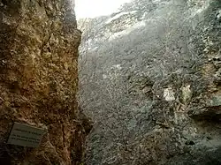 Narrow rocky gorge. A plaque with Chinese text is attached to the rock.