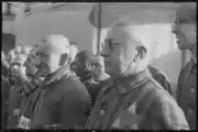 Sachsenhausen detainee with glasses in the foreground wears a two-color ID-emblem