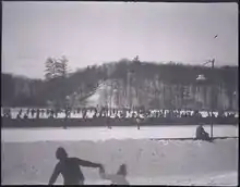 group of persons skating with hockey sticks playing ice hockey on a frozen pond